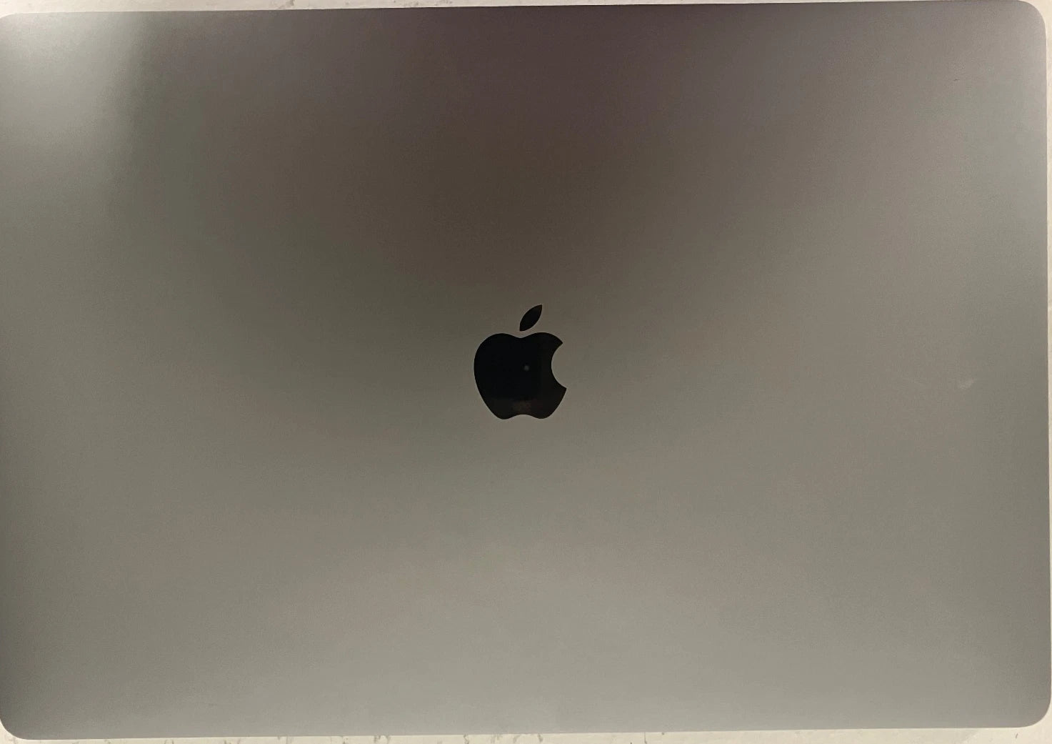 Back view of a laptop with Apple logo on a metallic surface