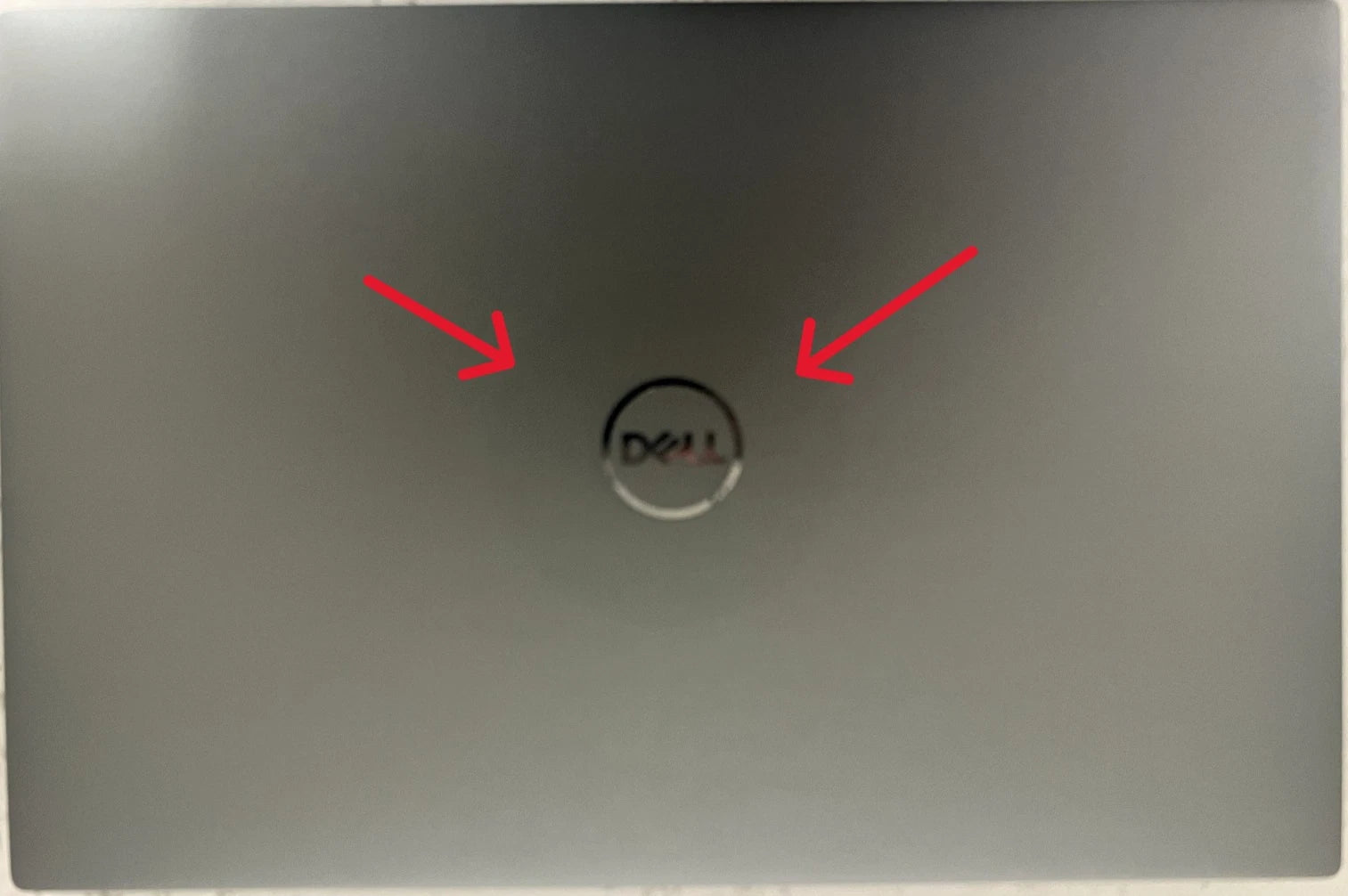Laptop with Dell logo on the back, indicated by red arrows.