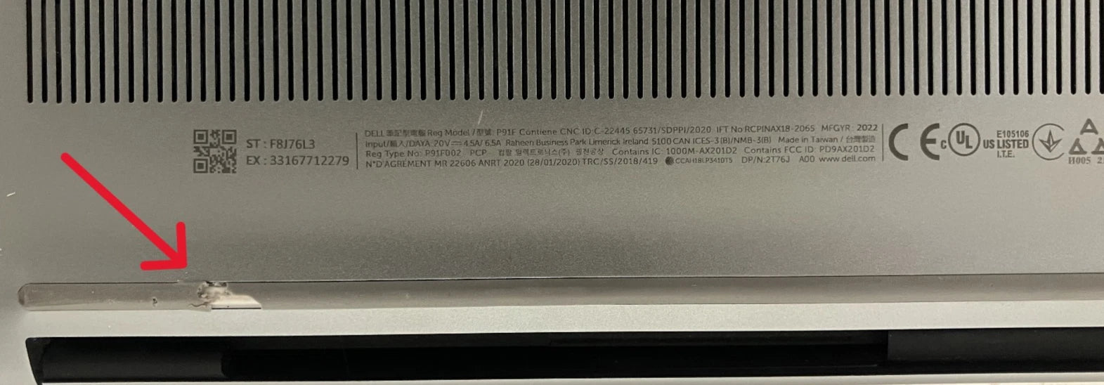 Back panel of a computer with text and a red arrow pointing to a damaged rubber foot